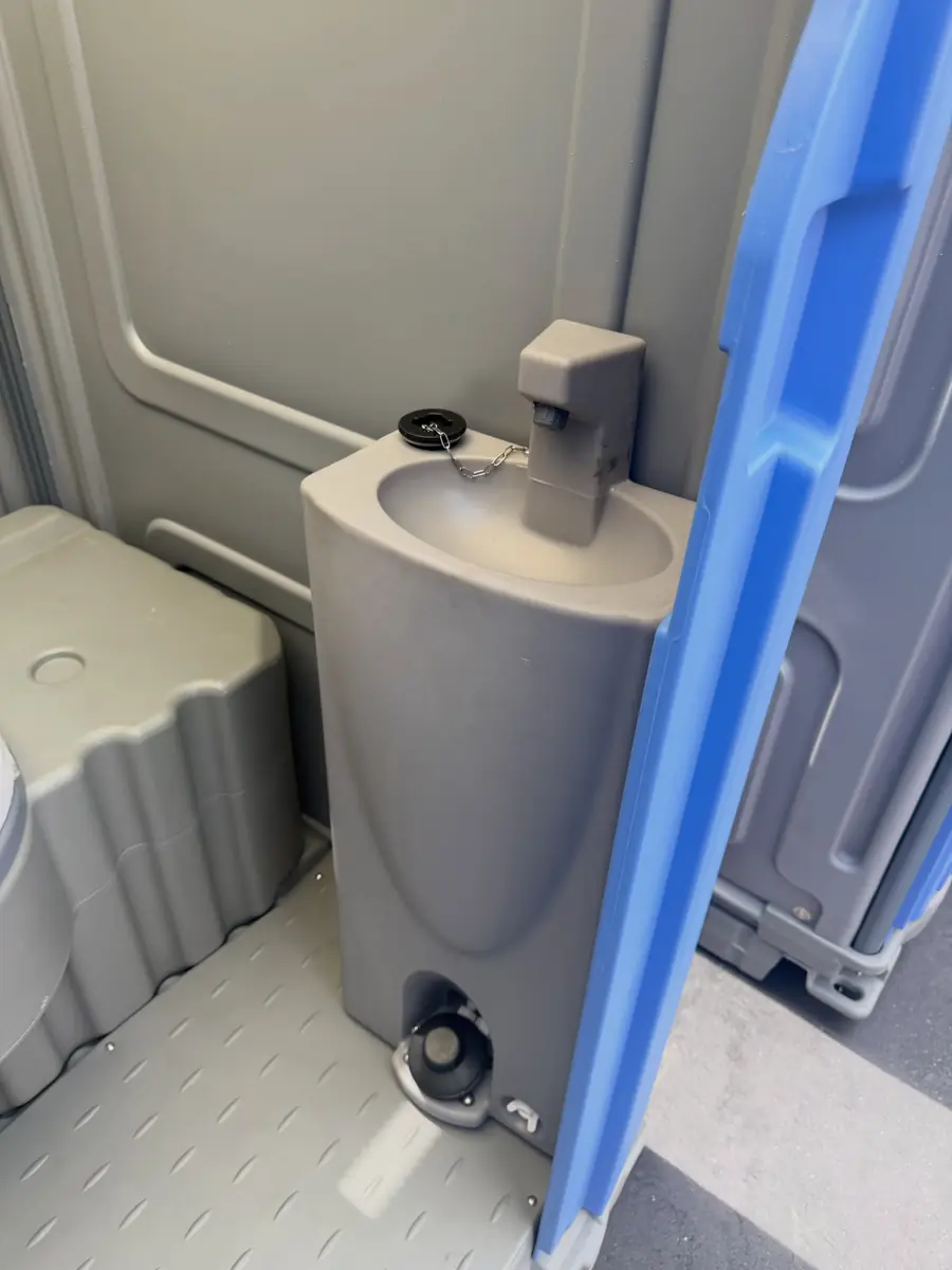 Inside a flushing porta potty with a foot-pump sink