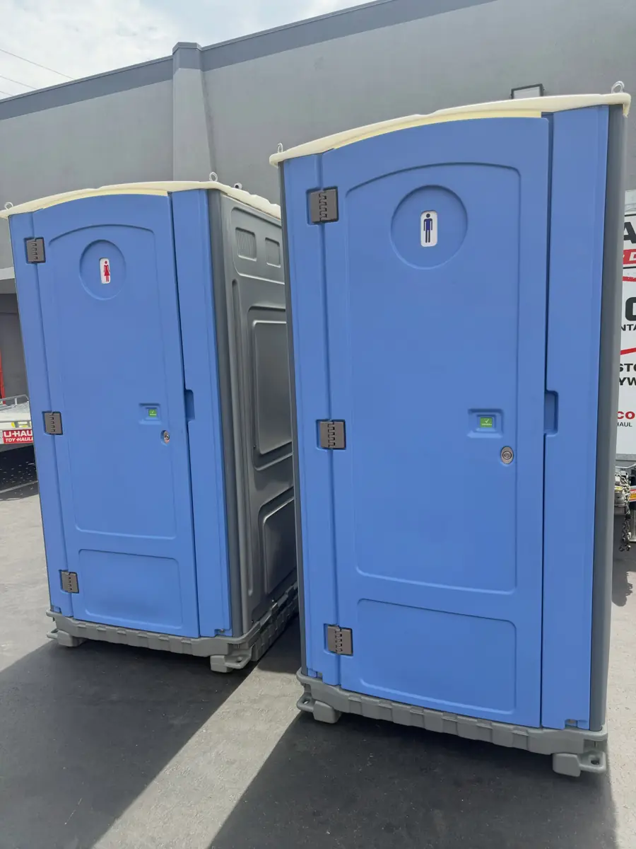 Two standard blue porta potties standing side by side